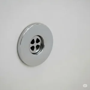 A close-up view of a standard bathtub overflow drain cover securely in place, showing the small opening for excess water.